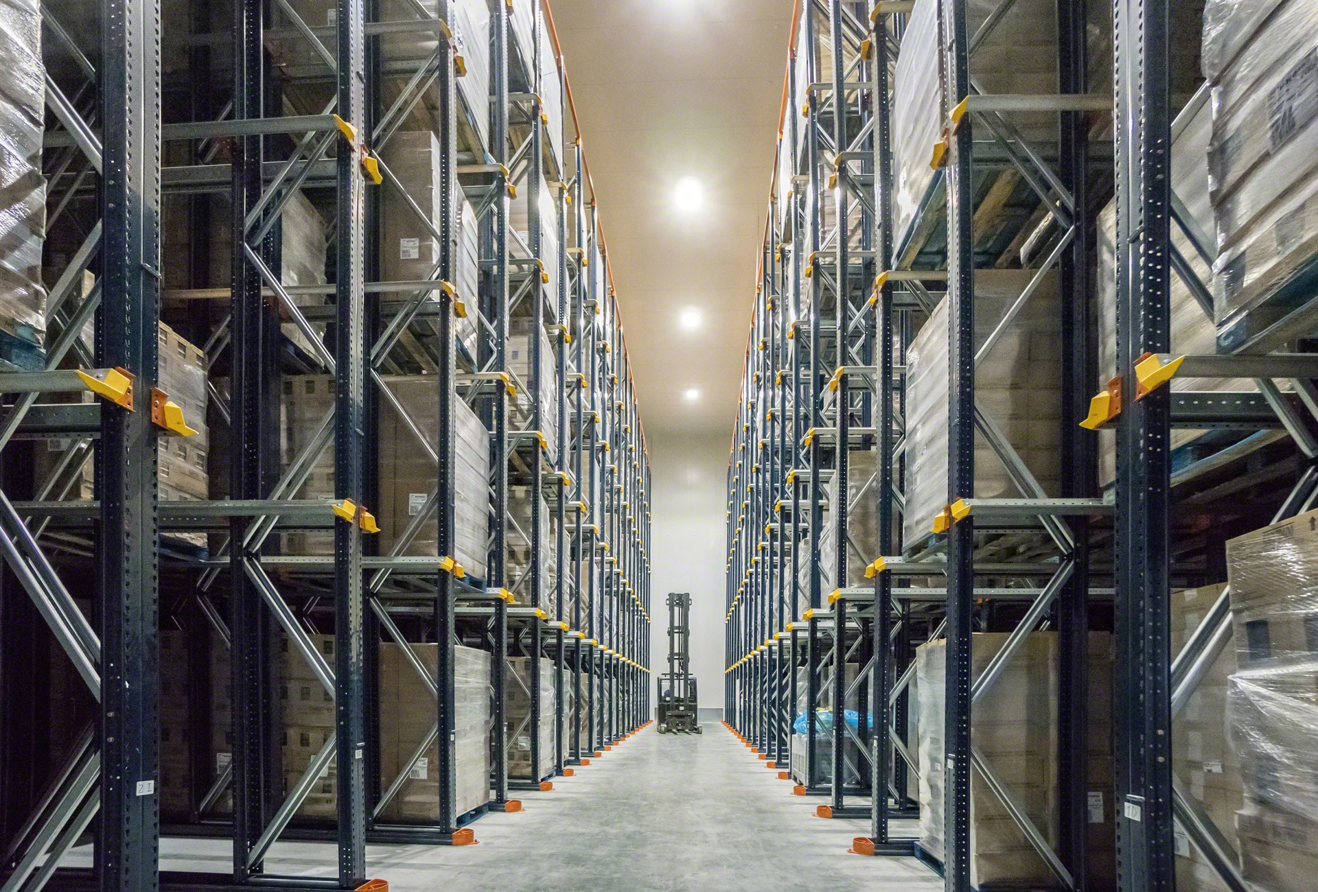 Forklift operating aisle beside dense pallet racking